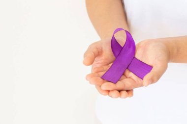 Hands holding purple or violet ribbon on white fabric with copy space. Pancreatic Cancer ,Testicular Cancer Awareness, Cancer Survivor, Leiomyosarcoma, World Cancer Day. Healthcare, insurance concept. clipart