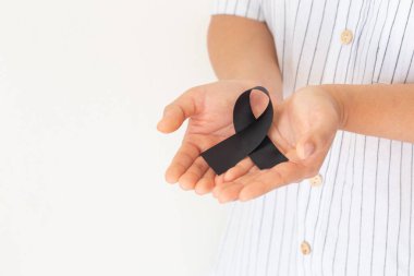 Beyaz arka planda siyah kurdele, fotokopi alanı, Mayıs ayı cilt kanseri farkındalığının sembolü, melanom kanseri, sembolik kurdele. Sağlık sigortası konsepti.