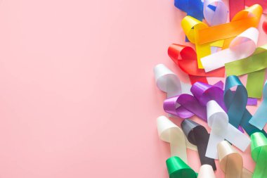 Renkli kurdeleler üst görünümde pastel pembe arka planda, metin için fotokopi alanı ile yatıyordu. 4 Şubat 'taki Dünya Kanser Günü kampanyası konsepti, kanser farkındalığı. Ulusal Kanser Kurtulma Günü.