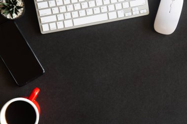Laptop, akıllı telefon ve bir fincan kahveli diğer iş malzemeleri olan siyah masa ofisi. Metni kopyalamak için üst görünümü kullan. Desenci çalışma alanı düz masa üzerinde temel elementler yatıyordu.