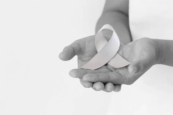 Mão Segurando Fita Cinza Fundo Tecido Branco Conscientização Sobre Câncer — Fotografia de Stock