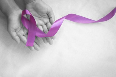 Hands holding purple or violet ribbon on white fabric with copy space. Pancreatic Cancer ,Testicular Cancer Awareness, Cancer Survivor, Leiomyosarcoma, World Cancer Day. Healthcare, insurance concept. clipart