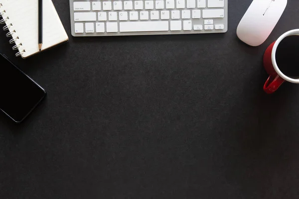 Laptop, akıllı telefon ve bir fincan kahveli diğer iş malzemeleri olan siyah masa ofisi. Metni kopyalamak için üst görünümü kullan. Desenci çalışma alanı düz masa üzerinde temel elementler yatıyordu.