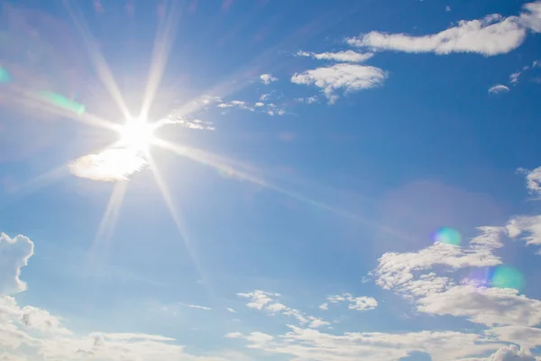 natural lens flare and radiating rays in a blue sky with clouds