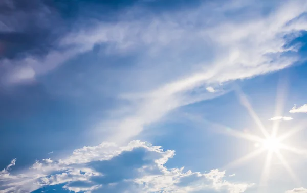 Natural lens flare and radiating rays in a blue sky with clouds — Stock Photo, Image