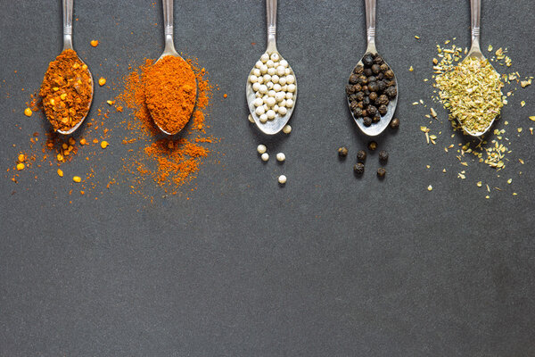 five type of spices and herb on the spoon on black stone backgro