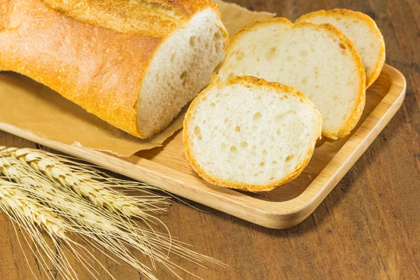 Pão e trigo no fundo de madeira, tonificação quente, seletiva f — Fotografia de Stock
