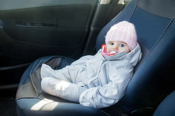 Newborn in car sitting on front seat dressed for winter — Stock Photo, Image