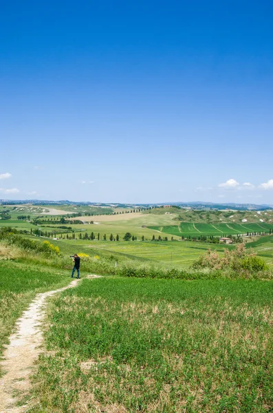 Siena, Italia, 31 de mayo de 2015 - Fotógrafo de paisaje bajo el cielo azul en colinas —  Fotos de Stock