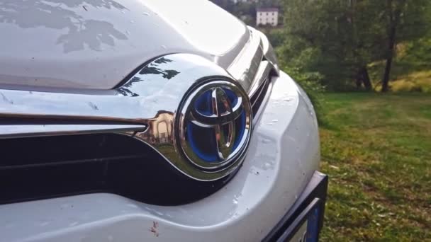 Logo de Toyota en la parte delantera blanco coche capucha naturaleza hierba fondo panorámica — Vídeos de Stock