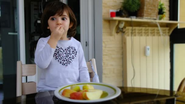 Criança come uma maçã cortada na varanda da casa. as maçãs são um alimento saudável na dieta — Vídeo de Stock