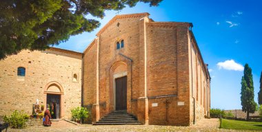 Güneşli bir günde, arka planda çiçekleri yatay panoramik formatlarda sulayan keşişlerle güzel antik bir manastır.