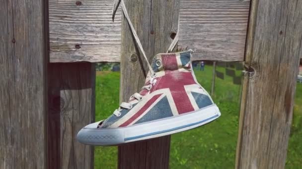 Hänga brittiska flagga sneakers skor till staket - hipster skor återanvändning i naturlig bakgrund — Stockvideo