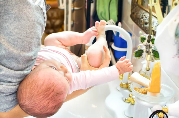 Мытье новорожденного ребенка в раковине ванной комнаты — стоковое фото