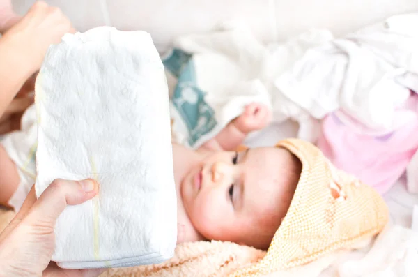 Föräldrarnas hand håller stack av blöjor baby på skötbord — Stockfoto