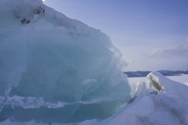 Bolshoe Gölü 'ndeki buz mırıltıları Krasnoyarsk Krai Sibirya Güneşli bir gün mavi gökyüzü beyaz masmavi kar şeffaf buzlar içinde donmuş taşlar. Donmuş göl dalgaları.