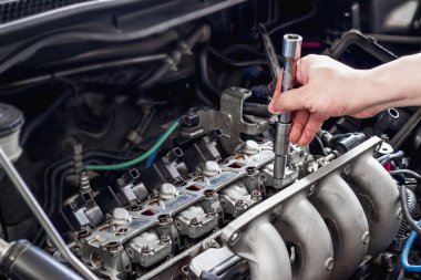 Motor odası servis konseptinde otomobil valf sistemini kontrol eden bir adam verin.