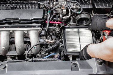 Aksiyon araba servisi konsepti: Bir adamın üzerini değiştirmesini sağlayın ve makine dairesindeki hava filtresini kontrol edin