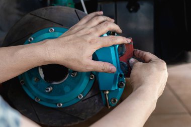 El teknisyeni fren balatalarını takviyeye takıyor ve el koyma önleyici fren pedi araba konseptine uyguluyor.