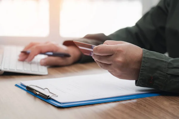 A man hold credit card in hand and in put credit card number in desktop computer for Payment bills online working on line concept