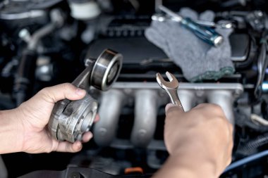 Bir teknisyenin elindeki İngiliz anahtarı Kemer Gerilme Makarası eski parça araba motoru yedek parçaların makine dairesine yerleştirilmesi