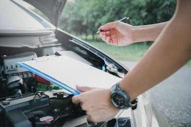 Konsept üzerinde, araba hizmet merkezinin çalışanları arızalı aracın bakım ve hizmet notlarını kontrol ediyor.