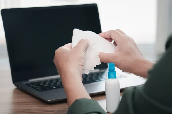 Close up hand a man cleaning and disinfection of workspace. Disinfecting wipes to wipe surface of desk , laptop, mouse at office. Stop the spread