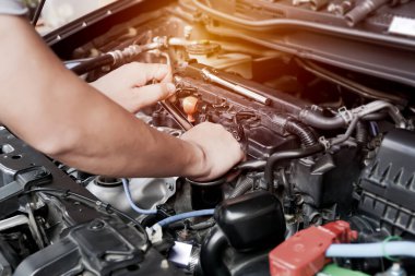 Teknisyen, motor odası servis konsepti ve bakımında benzinli arabanın bujisini sökmek için İngiliz anahtarı kullanır 