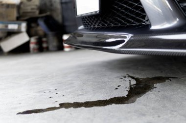 Aracın motor yağı lekeleri araba yol servisi fotoğraf konseptine park edildiğinde arabanın altına sızar.