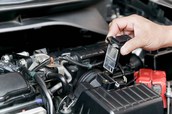Close up hand a Technician remove airflow sensor in the engine room car for check and cleaning in service concept