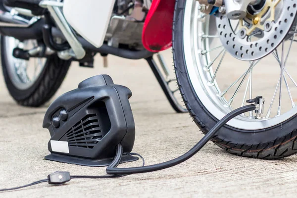 コンセプト空気圧を確認し 道路上の電気ポンプでオートバイでタイヤの空気を充填自動車の基本的なメンテナンス — ストック写真