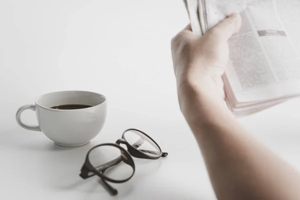 Biały Kubek Kawy Szklanki Człowiek Czytający Gazetę Białym Stole — Zdjęcie stockowe