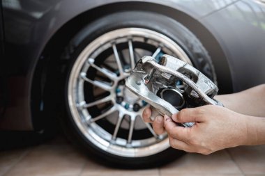 Araba servisi stop sistemi kavramı: arkaplanda bir adam ve bir tekerlek olan arabanın kalibreli frenini kapat