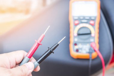 Kapat Bir adam dijital multi-metre veya elektrik kontrol volt pil ile motosiklet servis kavramı kullanın 