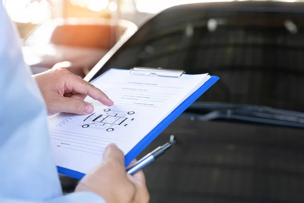 Insurance officer check point of car accident on clipboard while examining before damages are paid to the garage