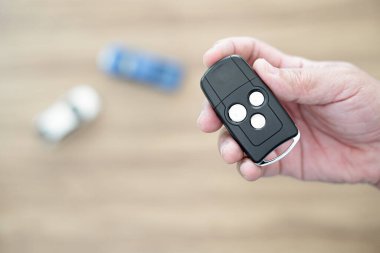 Anahtar araba elinde. Kilidi açıp kilitlemek için bir adam. Arka planda oyuncak araba olan bir araba.