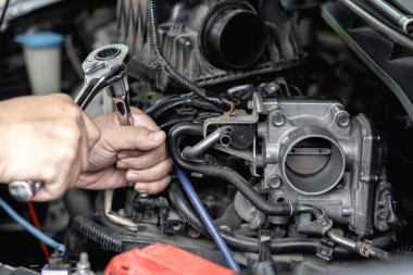 İngiliz anahtarını elinle kapat. Bir adam araba servisi motorunun gaz vanası temizleme ve onarım: araba servisi konsepti fotoğrafı