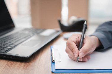 Bir adam, masadaki dizüstü bilgisayar hazırlık teslimat paketini kullanarak posta kutusunu paketlerken ve web sitesinin perakende siparişini kontrol ederken not alıyor: çevrimiçi küçük işletme mağazası 