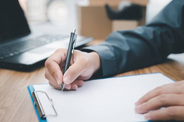 Dağıtım listesini kontrol eden ve beyaz kağıt dosya ataç panosunu yazan bir adam veri formu bilgisayarı kullanarak müşterilere bilgi iletiyor. 