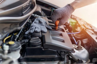 Tamirci makine dairesinde motor yağı seviyesini kontrol ediyor. Otomobil tamirhanesinde. İş konsepti için servis fotoğrafı.