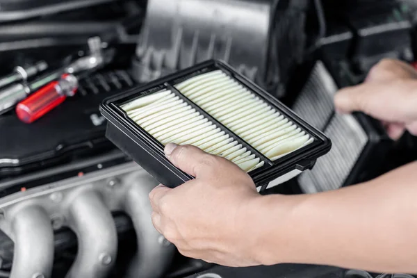 Service man replace the old engine air filter compared to the new one in engine room : Home service car concept