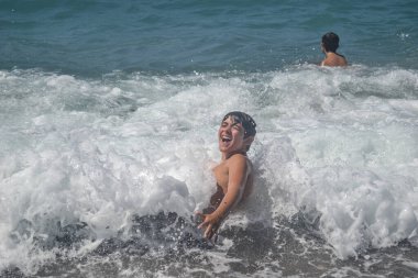 Çocuklar deniz dalgalarıyla sürüklenip gidiyorlar.