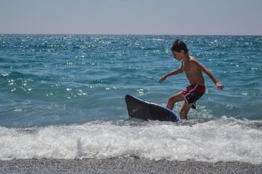 Sörf tahtasında sörf yapan bir çocuk