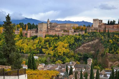 Sonbaharda bulutlu bir günde Alhambra 'nın manzarası, Albaisin' in yeşil ve sarı yapraklı ağaçları ve evleri olan orman.