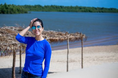 Brezilya 'nın kuzeydoğusundaki Parnaiba Nehri Deltasında turizm. Kum tepeleri ve paradisiacal manzaralar. Kumsalda güneş gözlüğü kullanan esmer kadın. Rüzgardaki kıvırcık saçlar.