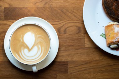Mug of cappuccino on the wooden table for a good breakfast and muffins on a plate