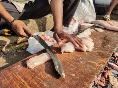 Tahtada taze balık filetosu. Hindistan 'da balık pazarı. Satıcı büyük eğri bir bıçakla balık filetosu kesiyor.