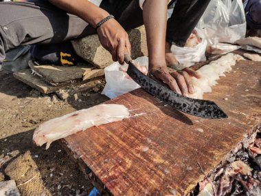 Tahtada taze balık filetosu. Hindistan 'da balık pazarı. Satıcı büyük eğri bir bıçakla balık filetosu kesiyor.