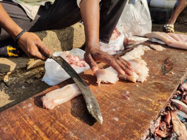 Taze balık filetosu. Hindistan 'da balık pazarı. Satıcı büyük eğri bir bıçakla balık filetosu kesiyor.