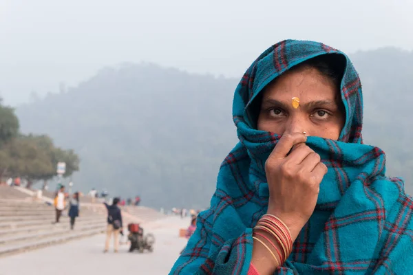 The Indian woman covers her face with a green handkerchief.  Portrait of an ordinary native on the embankment of the Sacred Ganges